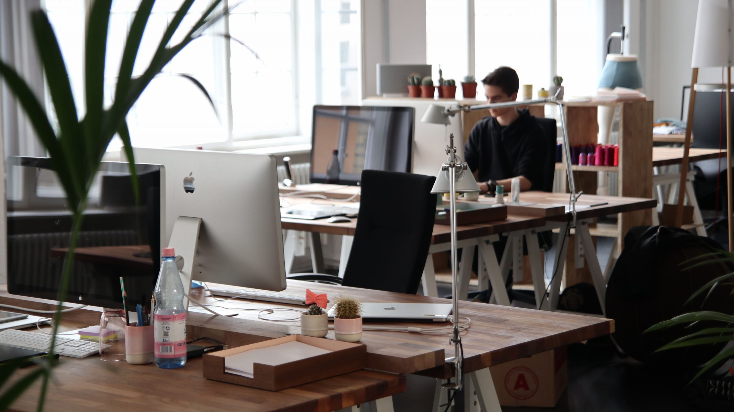 Modern office space with desks, computers, and plants, reflecting the hybrid approach to work.