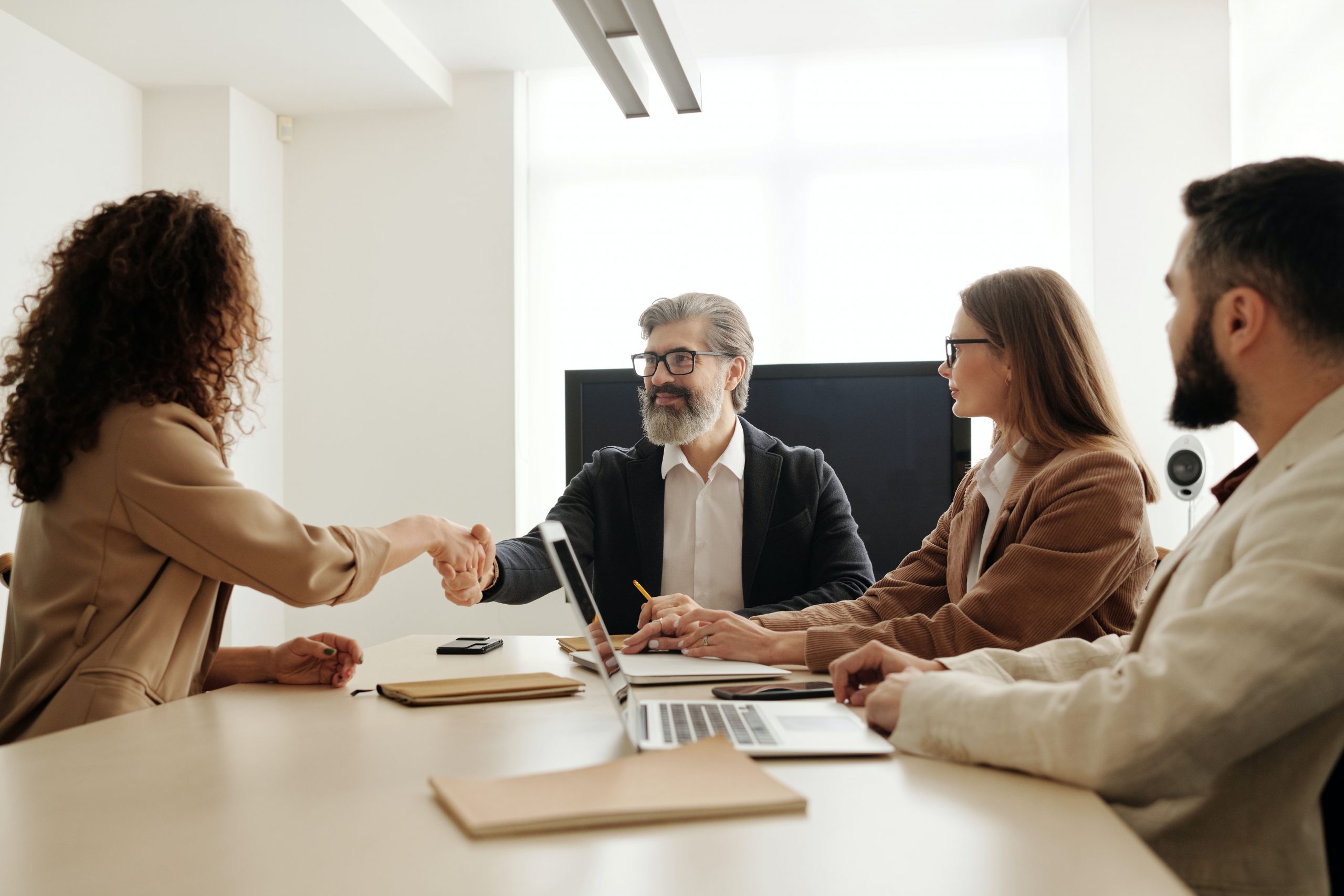 Business meeting: woman shaking hands with a man across a conference table.