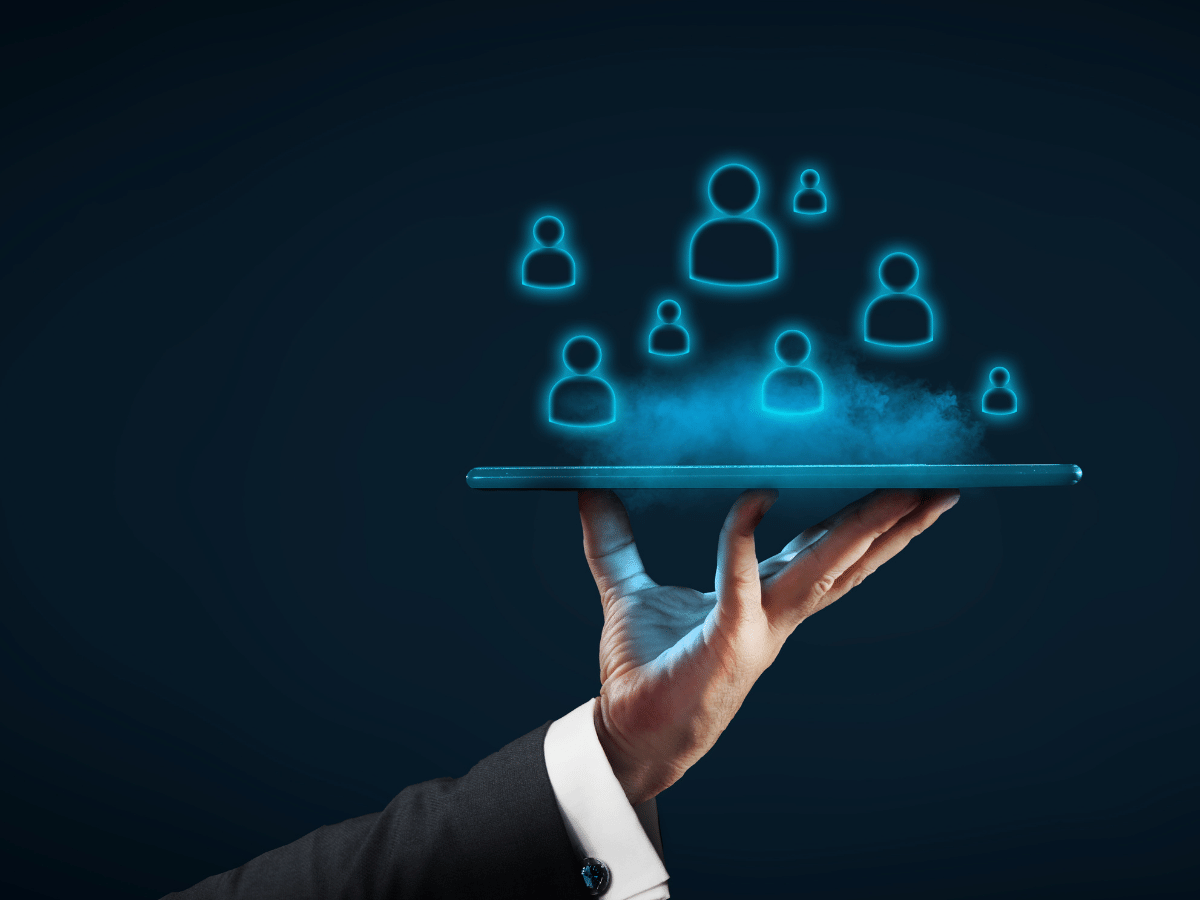 Hand holding tablet displaying glowing people icons. Outsourced recruitment concept.